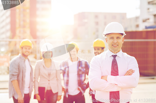 Image of group of smiling builders in hardhats outdoors