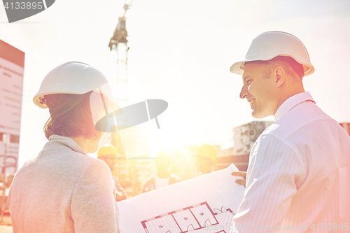 Image of happy architects with blueprint at building