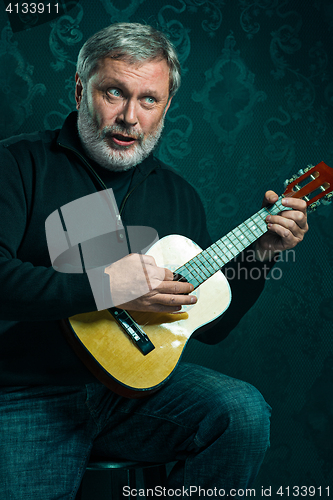 Image of Studio portrait of senior man with guitar.