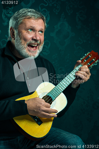 Image of Studio portrait of senior man with guitar.