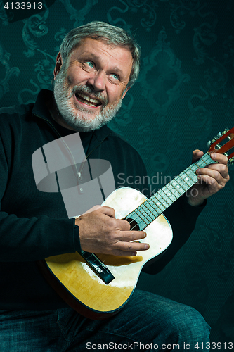 Image of Studio portrait of senior man with guitar.