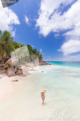 Image of Woman enjoying Anse Patates picture perfect beach on La Digue Island, Seychelles.