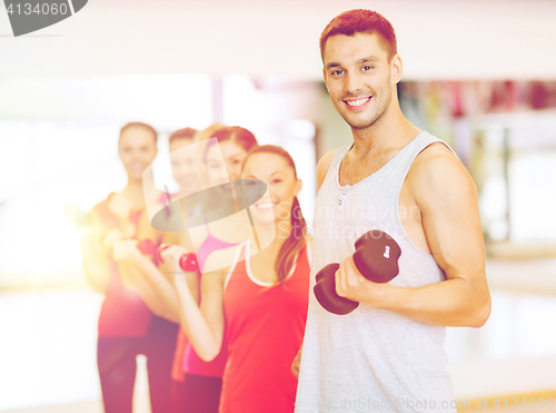 Image of group of smiling people with dumbbells in the gym