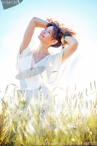 Image of pretty happy woman in bright clothing among spikes in field
