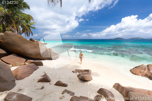 Image of Woman enjoying Anse Patates picture perfect beach on La Digue Island, Seychelles.