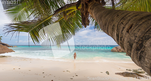 Image of Woman enjoying Anse Patates picture perfect beach on La Digue Island, Seychelles.