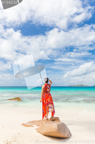 Image of Woman relaxing at Anse Patates picture perfect beach on La Digue Island, Seychelles.