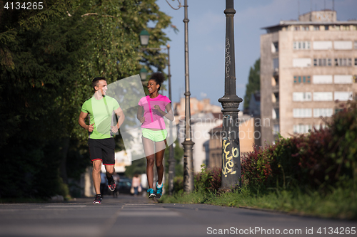 Image of young smiling multiethnic couple jogging in the city