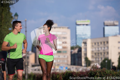 Image of young smiling multiethnic couple jogging in the city