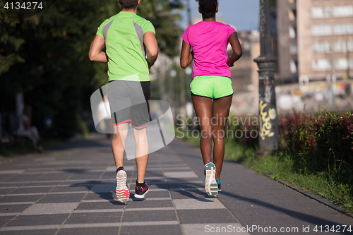 Image of young smiling multiethnic couple jogging in the city