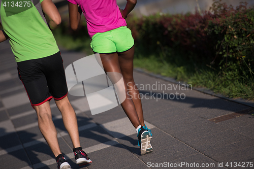 Image of young smiling multiethnic couple jogging in the city
