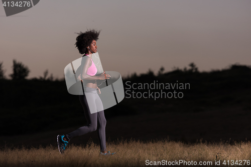 Image of Young African american woman jogging in nature