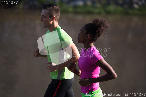 Image of young smiling multiethnic couple jogging in the city