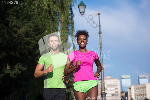 Image of young smiling multiethnic couple jogging in the city