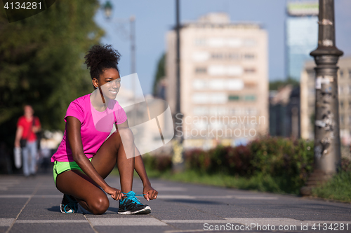 Image of African american woman runner tightening shoe lace