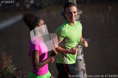 Image of young smiling multiethnic couple jogging in the city