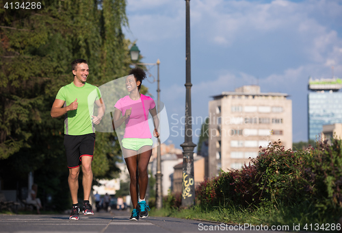 Image of young smiling multiethnic couple jogging in the city