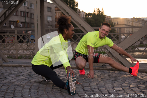 Image of jogging couple warming up and stretching in the city