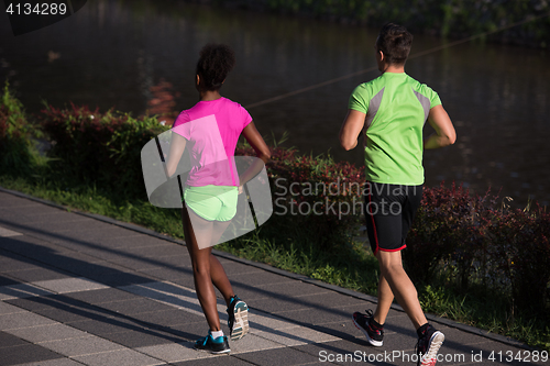 Image of young smiling multiethnic couple jogging in the city