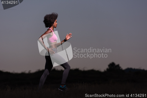 Image of Young African american woman jogging in nature