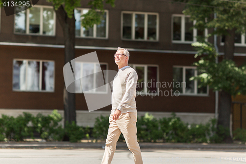 Image of senior man walking along summer city street