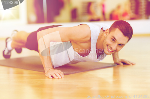 Image of smiling man doing push-ups in the gym