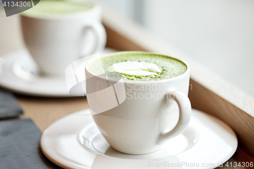 Image of white cup of matcha green tea latte on table