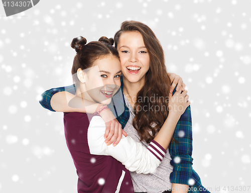 Image of happy pretty teenage girls hugging over snow