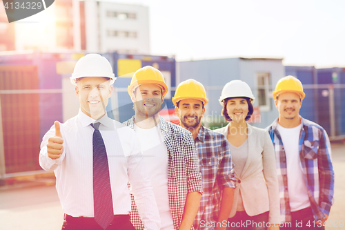 Image of group of smiling builders in hardhats outdoors