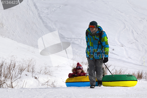 Image of Father and daughter with snow tube at ski resort