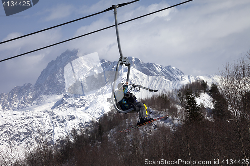Image of Skiers on ski-lift in snow mountains at winter sun day