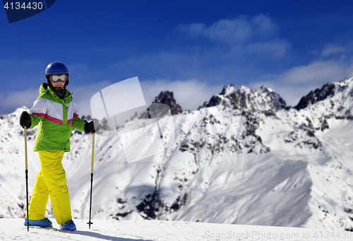 Image of Young skier with ski poles in snow mountains at sun winter day