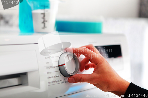 Image of woman hand adjusting washing machine