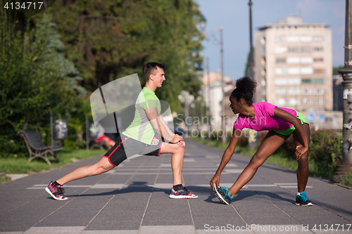 Image of jogging couple warming up and stretching in the city