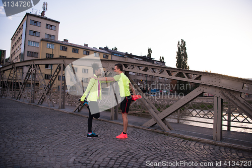 Image of jogging couple warming up and stretching in the city