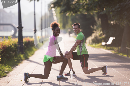 Image of jogging couple warming up and stretching in the city