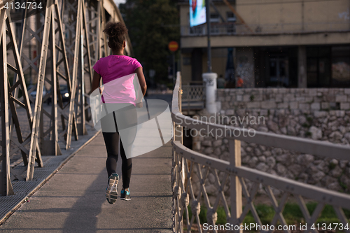 Image of african american woman running across the bridge