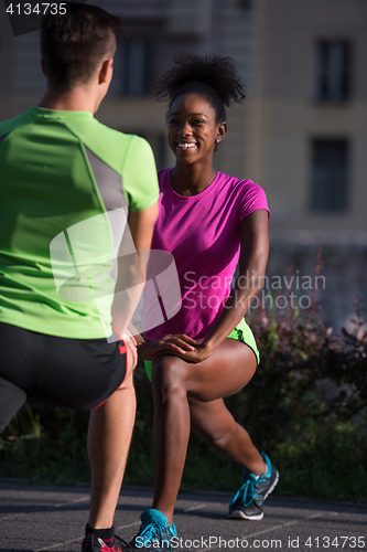 Image of jogging couple warming up and stretching in the city