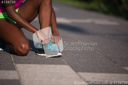 Image of African american woman runner tightening shoe lace