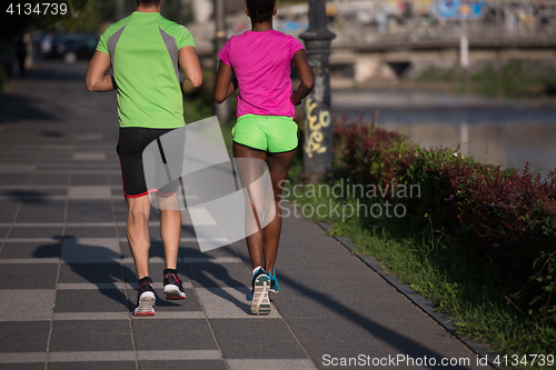 Image of young smiling multiethnic couple jogging in the city