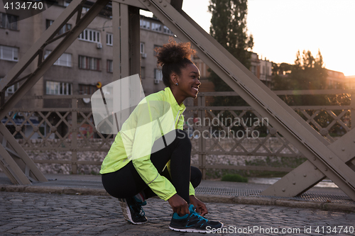 Image of African american woman runner tightening shoe lace