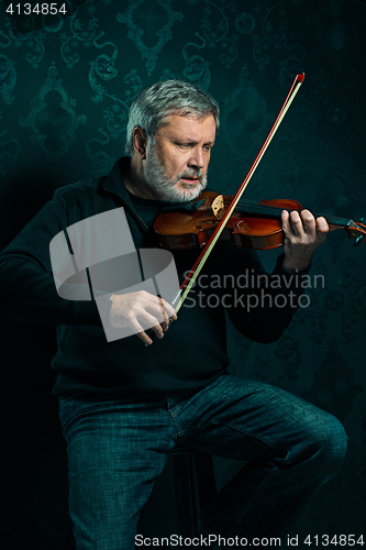 Image of Senior musician playing a violin with wand on black background