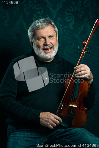 Image of Senior musician playing a violin with wand on black background