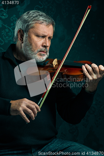 Image of Senior musician playing a violin with wand on black background