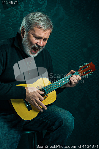 Image of Studio portrait of senior man with guitar.