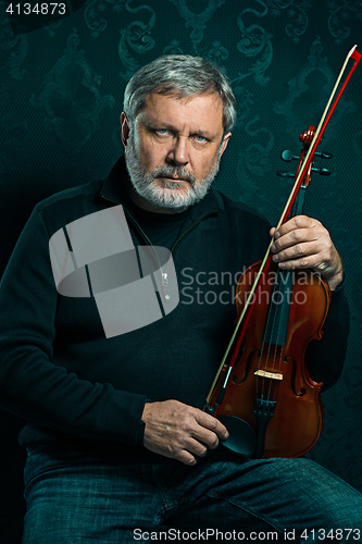 Image of Senior musician playing a violin with wand on black background