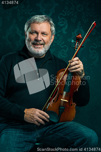 Image of Senior musician playing a violin with wand on black background