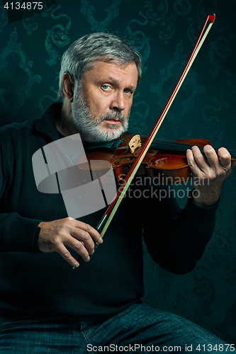 Image of Senior musician playing a violin with wand on black background