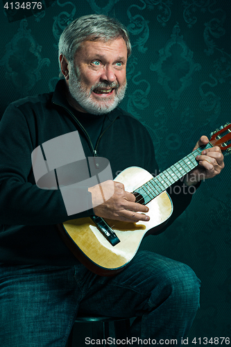 Image of Studio portrait of senior man with guitar.