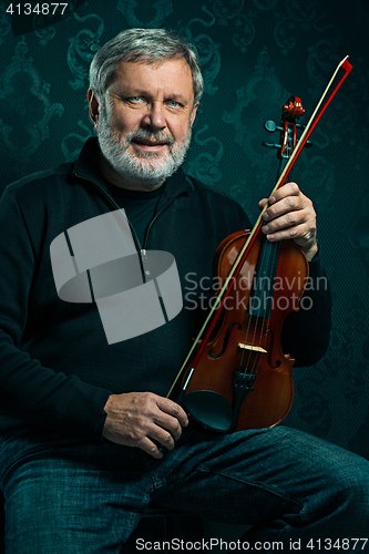 Image of Senior musician playing a violin with wand on black background